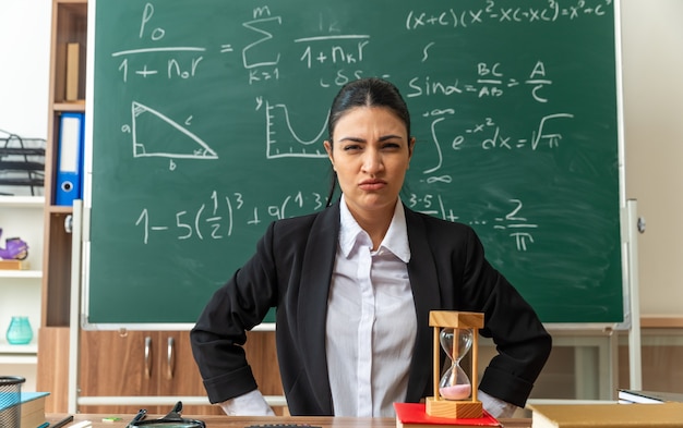 una giovane insegnante scontenta si siede a tavola con materiale scolastico in classe