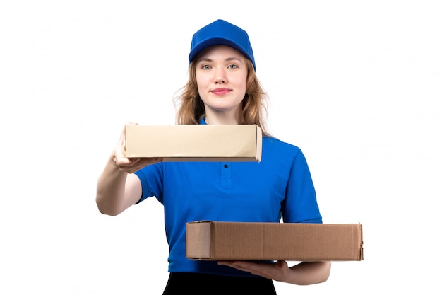 Una giovane lavoratrice femminile del corriere femminile di vista frontale dei pacchetti di consegna dell'alimento della tenuta di servizio di consegna dell'alimento che sorride sul bianco