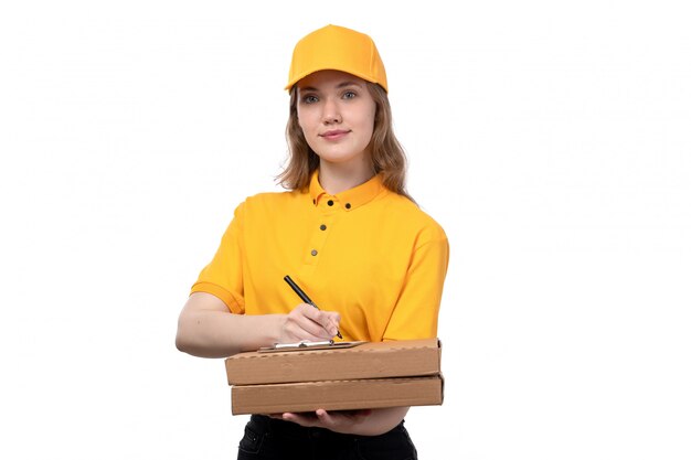 Una giovane lavoratrice femminile del corriere femminile di vista frontale delle scatole e del blocco note sorridenti di consegna della tenuta di servizio di distribuzione di alimenti su bianco
