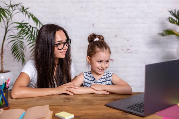 Una giovane madre con la figlia piccola sta acquistando su Internet al personal computer. Concetto di acquisto in linea della famiglia