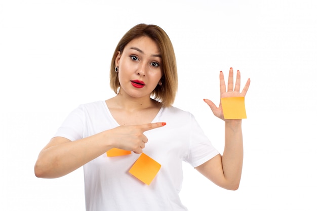 Una giovane signora di vista frontale in camicia bianca con le note arancio che posano mostrando la nota arancio sul bianco