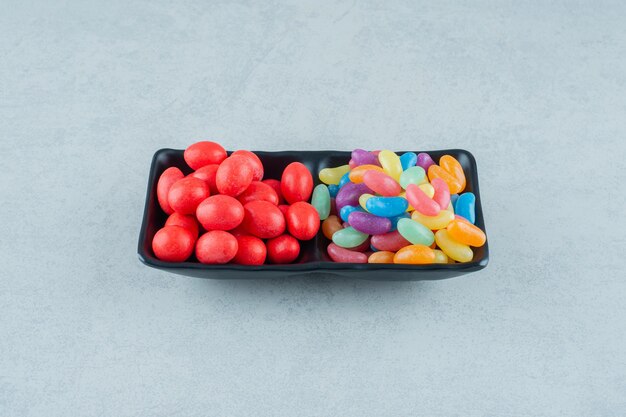 Una lavagna piena di caramelle colorate di fagioli su una superficie bianca
