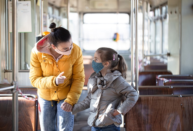 Una madre con un bambino su un trasporto pubblico vuoto, con indosso maschere durante una pandemia di coronavirus.