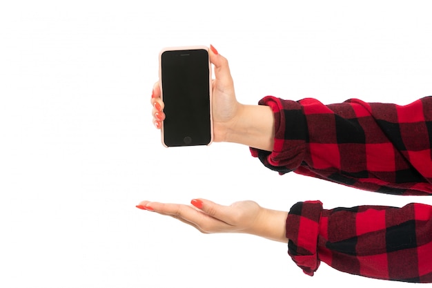 Una mano femminile di vista frontale in camicia a quadretti nero-rossa che tiene smartphone mostrando il palmo aperto sul bianco