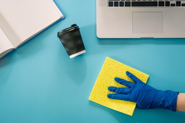 Una mano in un guanto di gomma pulisce il posto di lavoro piatto