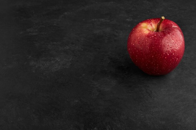 Una mela rossa isolata sulla superficie nera.