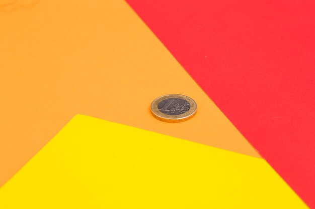 Una moneta da un euro sul rosso; sfondo giallo e arancione