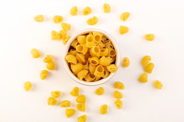 Una pasta gialla cruda della pasta asciutta italiana di vista superiore dentro la ciotola sul bianco