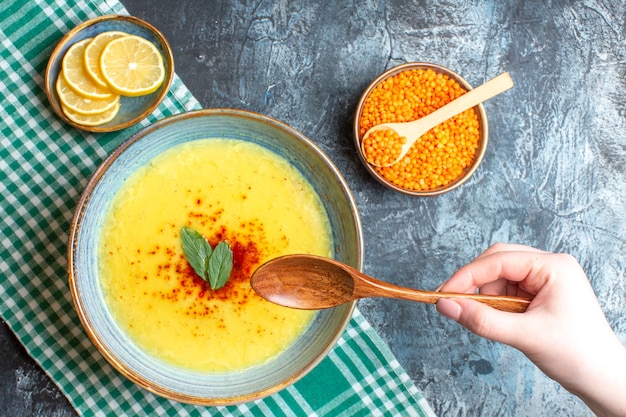 Una pentola blu con zuppa gustosa servita con menta e pepe accanto a un cucchiaio di legno di limone tritato