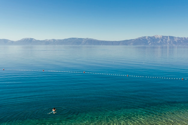 Una persona che nuota nel lago idilliaco blu