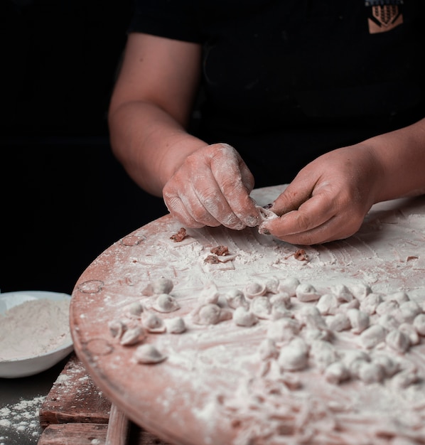 Una persona che produce manti turchi con pasta.