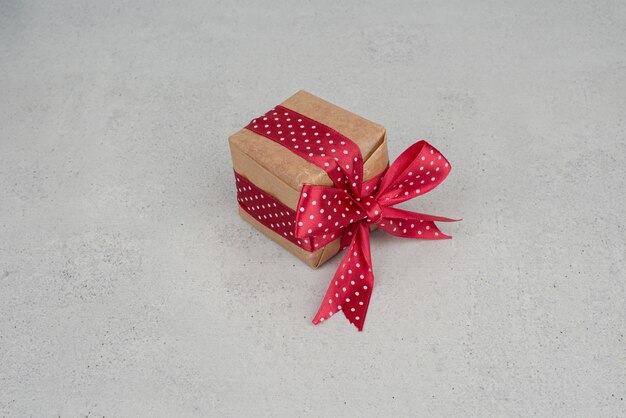 Una piccola confezione regalo con fiocco rosso su sfondo bianco.