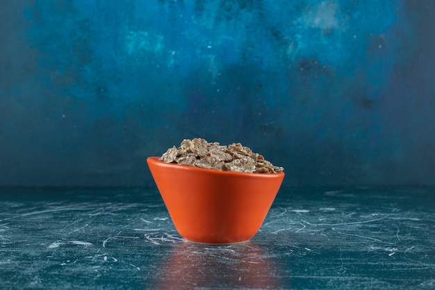 Una piccola porzione di cornflakes secchi, sullo sfondo blu. Foto di alta qualità