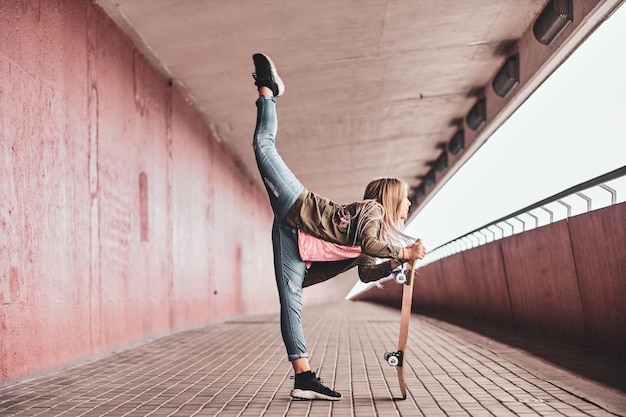 Una piccola ragazza adolescente allegra sta mostrando la sua performance mentre posa per il fotografo nel tunnel.