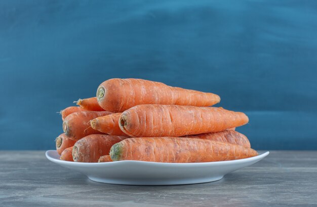 Una pila di carote nel piatto, sul tavolo di marmo.