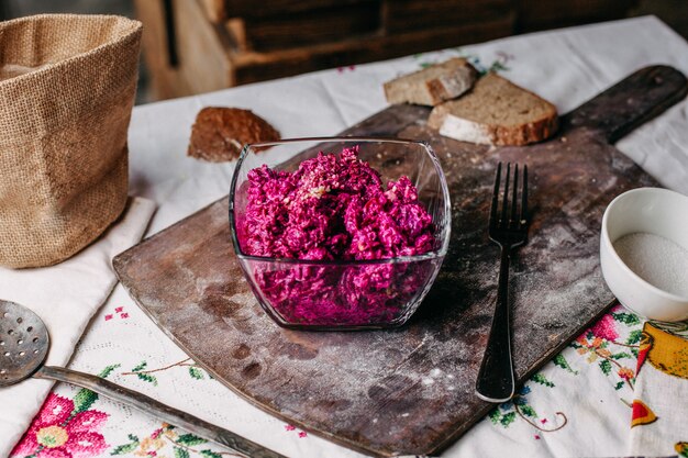 Una porpora dell'insalata della barbabietola di vista frontale affettata con le noci dentro il piatto trasparente ha salato le verdure saporite della vitamina piccante sullo scrittorio marrone