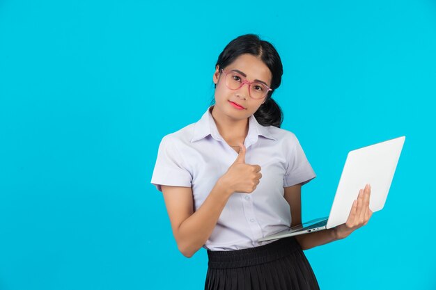 Una ragazza asiatica dello studente che tiene il suo taccuino su un blu.