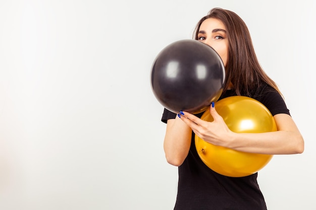 Una ragazza con palloncini e in piedi su sfondo bianco