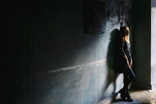 Una ragazza con una vista da sogno si appoggia a un muro in un caffè