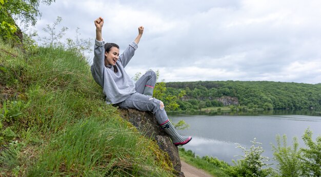 Una ragazza durante una passeggiata ha scalato una montagna in una zona montuosa e si rallegra.