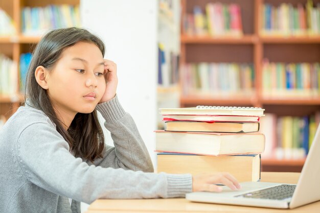 una ragazza è seduta a leggere un libro in biblioteca