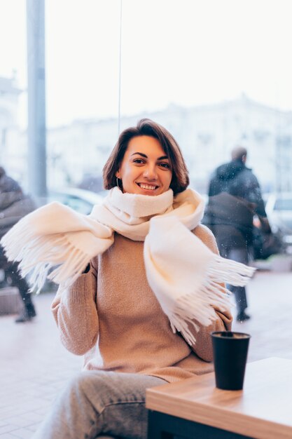 Una ragazza in un accogliente bar si riscalda con una tazza di caffè caldo