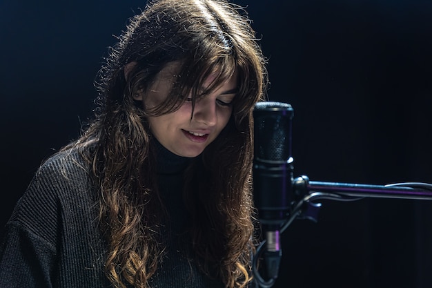 Una ragazza in uno studio di registrazione con un microfono professionale