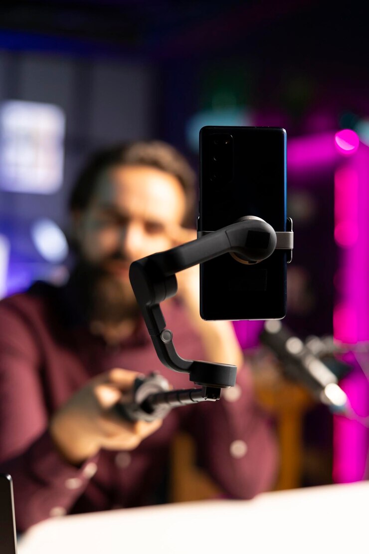 Foto gratuito una ripresa ravvicinata della telecamera del telefono cellulare utilizzata dall'uomo per registrare un vlog in un appartamento illuminato al neon