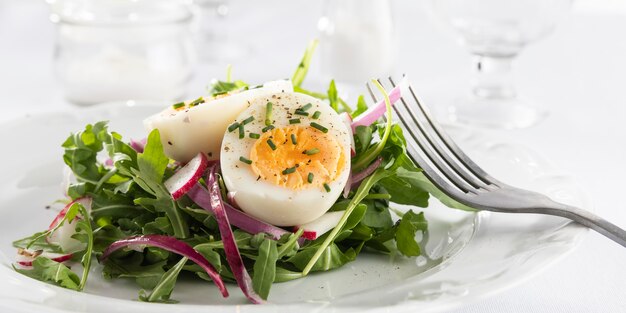 Una sana insalata con l'uovo su un piatto bianco