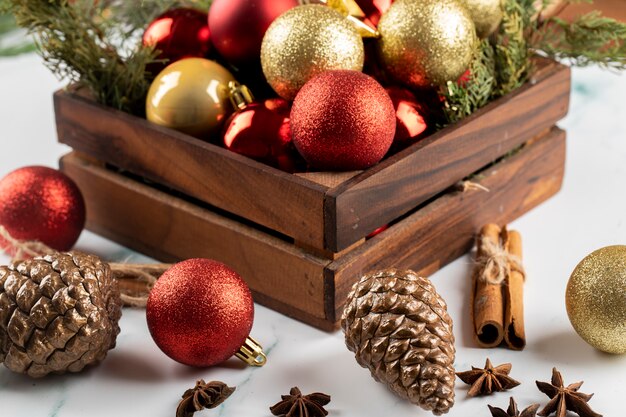 Una scatola di ornamenti rossi e dorati dell'albero di Natale sul tavolo.
