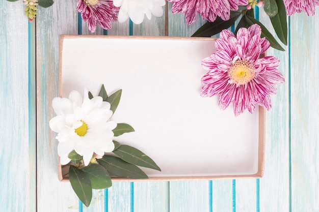 Una scatola vuota con fiori margherita e crisantemo