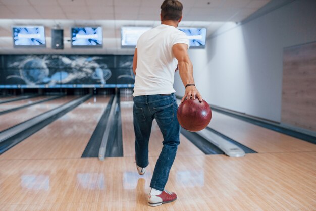 Una sola persona. Vista posteriore dell'uomo in abiti casual, giocare a bowling nel club