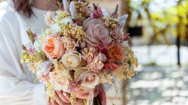 Una sposa con in mano un bouquet lussureggiante, vista ravvicinata, cerimonia nuziale