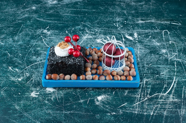 Una tavola blu con un pezzo di torta al cioccolato e noci di macadamia. Foto di alta qualità