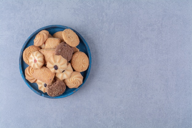 Una tavola di legno blu con deliziosi biscotti rotondi dolci su tela di sacco.