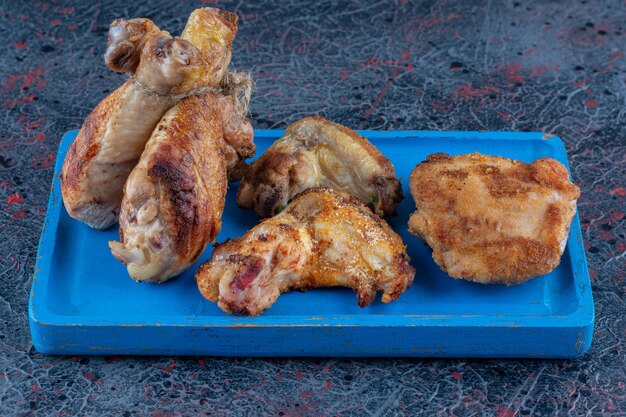 Una tavola di legno blu di carne di pollo alla griglia.