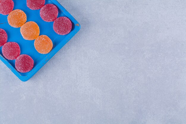 Una tavola di legno blu piena di marmellate zuccherate rosse e arancioni. Foto di alta qualità