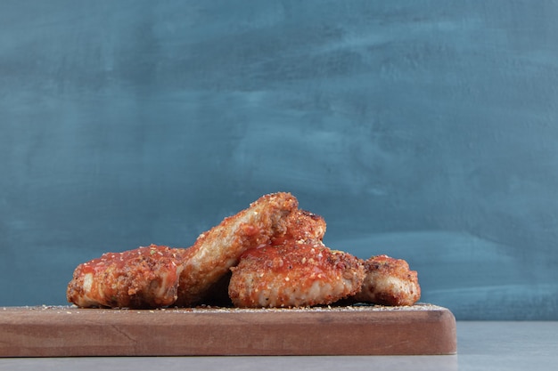 Una tavola di legno con carne di pollo fritta con gusto.