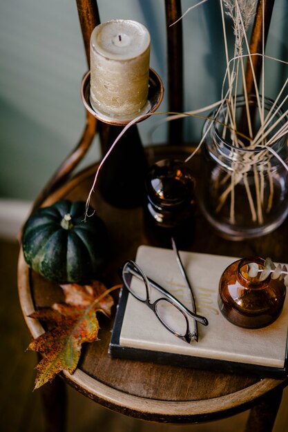 Una tavola di legno decorata con un tema autunnale con una candela aromatica, bicchieri, fiori secchi,