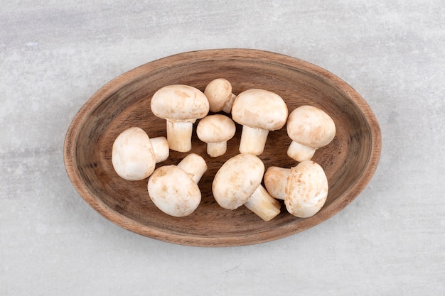 Una tavola di legno di funghi bianchi freschi sulla superficie di pietra.