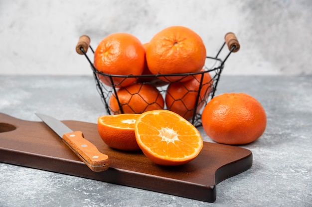 Una tavola di legno di succose fette di frutta arancione con un coltello sul tavolo di pietra.