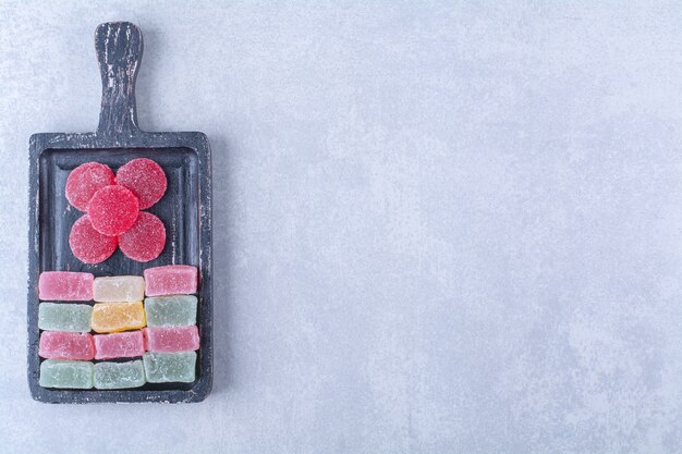 Una tavola di legno nera piena di caramelle colorate zuccherate