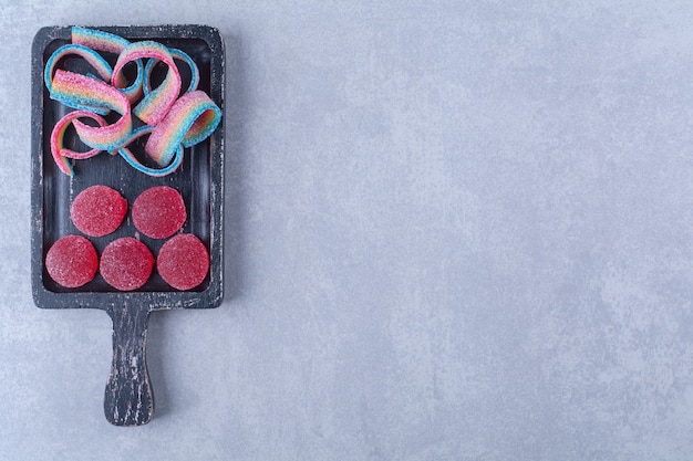 Una tavola di legno nera piena di caramelle colorate zuccherine.