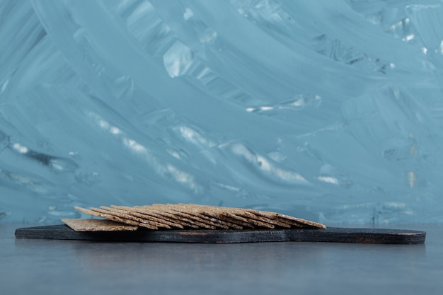 Una tavola di legno nera piena di graham di pane croccante.