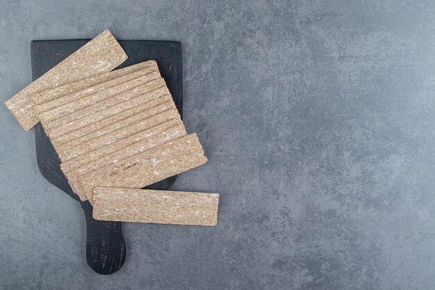 Una tavola di legno nera piena di graham di pane croccante.