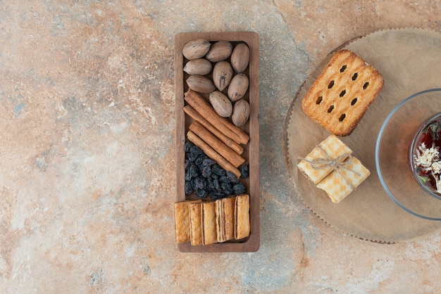 Una tavola di legno piena di biscotti dolci e una tazza di tisana