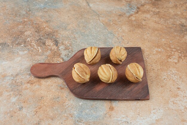 Una tavola di legno piena di biscotti dolci su sfondo di marmo