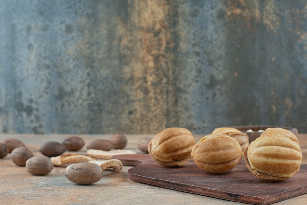 Una tavola di legno piena di biscotti dolci su sfondo di marmo