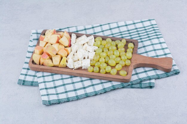 Una tavola di legno piena di formaggio bianco e frutta a fette. Foto di alta qualità