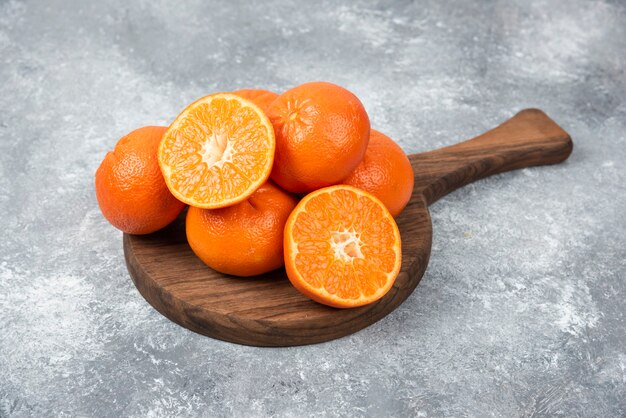 Una tavola di legno piena di frutti arancioni succosi con fette sul tavolo di pietra.